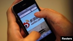 FILE - A man holds an iPhone as he visits Sina's Weibo (China's version of Twitter) microblogging site in Shanghai.