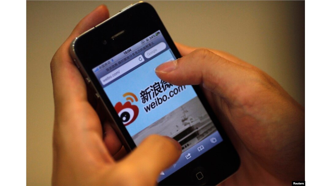 FILE - A man holds an iPhone as he visits Sina's Weibo (China's version of Twitter) microblogging site in Shanghai.