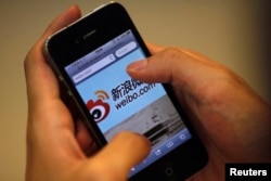 FILE - A man holds an iPhone as he visits Sina