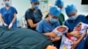 Perawat menunjukkan sepasang saudara kembar kepada ibu mereka (bawah) setelah mereka lahir di pusat bayi tabung sebuah rumah sakit di Xi'an, Provinsi Shaanxi. Foto: Reuters)