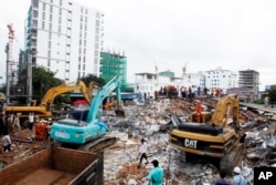 FILE - Rescuers try to remove the rubble at the site of a collapsed building in Preah Sihanouk province, Cambodia, Sunday, June 23, 2019.