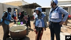 United Nations personnel look on as a worker serves food at a camp in Hodan district in Mogadishu, January 19, 2012
