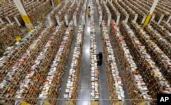 FILE - An Amazon.com employee stocks products in December 2013 in Phoenix as online shopping continues to boom.