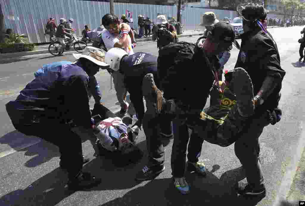Injured anti-government protesters are carried by other protesters after an explosion during a demonstration in Bangkok, Thailand, Jan. 17, 2014.
