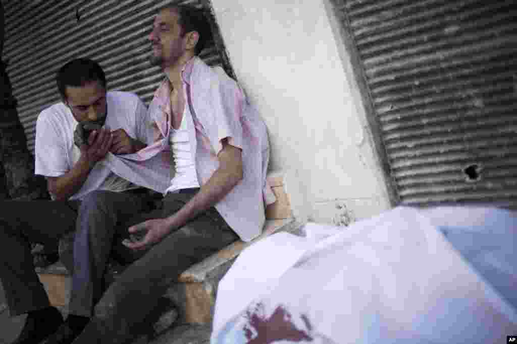 A Syrian man is comforted after the death of his brother, who witnesses say was shot by a Syrian Army sniper, outside Dar El Shifa Hospital in Aleppo, Syria, September 27, 2012.