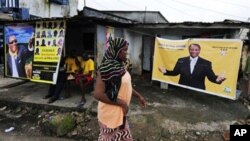 A woman walks in front a poster for Guinean presidential candidate, Alpha Conde, hung in front of the home of supporter for his party (file photo)