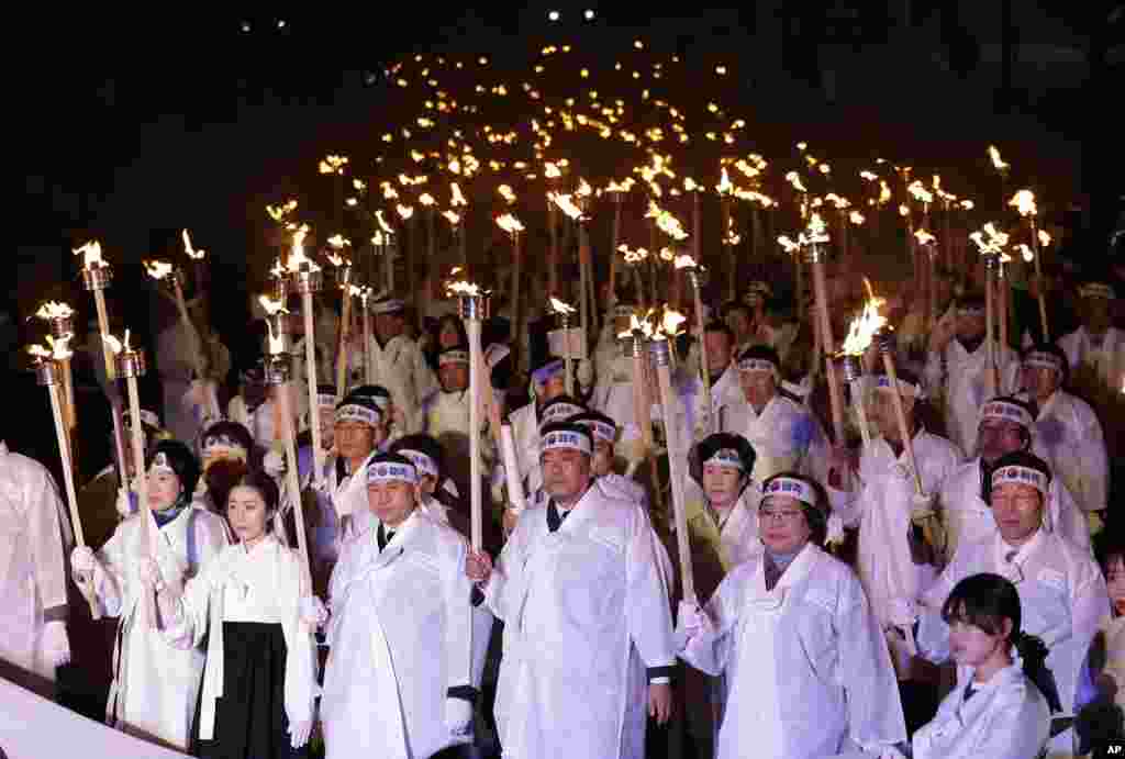 South Koreans wearing traditional Korean costumes carry torches as they march on the street during a ceremony to celebrate the March First Independence Movement Day.