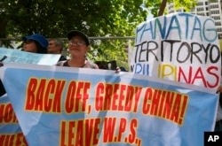 FILE - Protesters display placards in front of the Chinese Consulate to protest China's alleged continuing "militarization" of the disputed islands off the South China Sea including a plan to build a monitoring station on Scarborough Shoal, March 24, 2017.