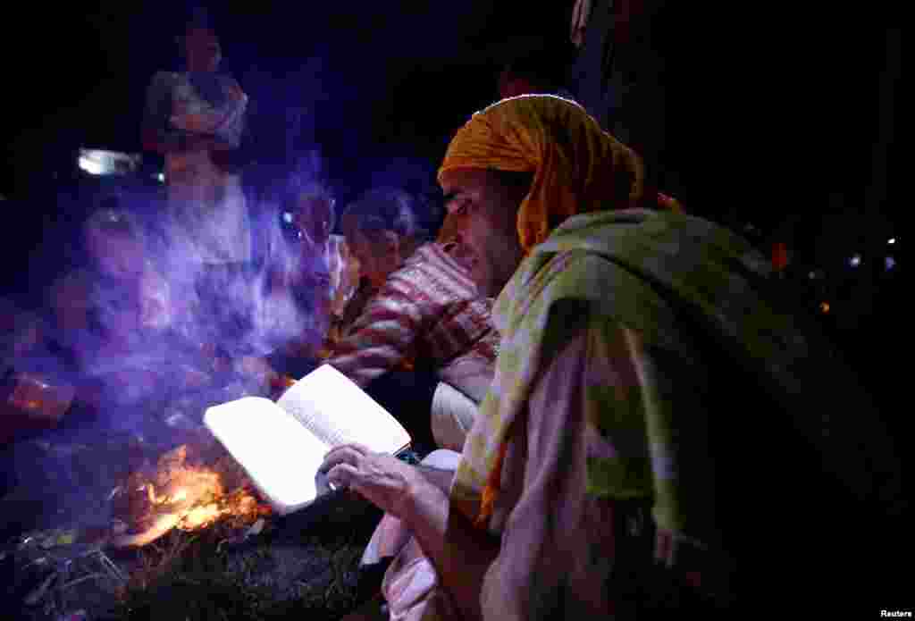 A Hindu priest recites prayers from a holy book while performing a ritual near the bank of Bagmati River during Kuse Aunse (Father&#39;s Day) at Gokarna Temple in Kathmandu, Nepal.