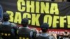 Riot police stand guard as protesters hold up a large anti-China banner outside the Chinese Consulate at the financial district of Makati city, east of Manila, Philippines, July 24, 2013.
