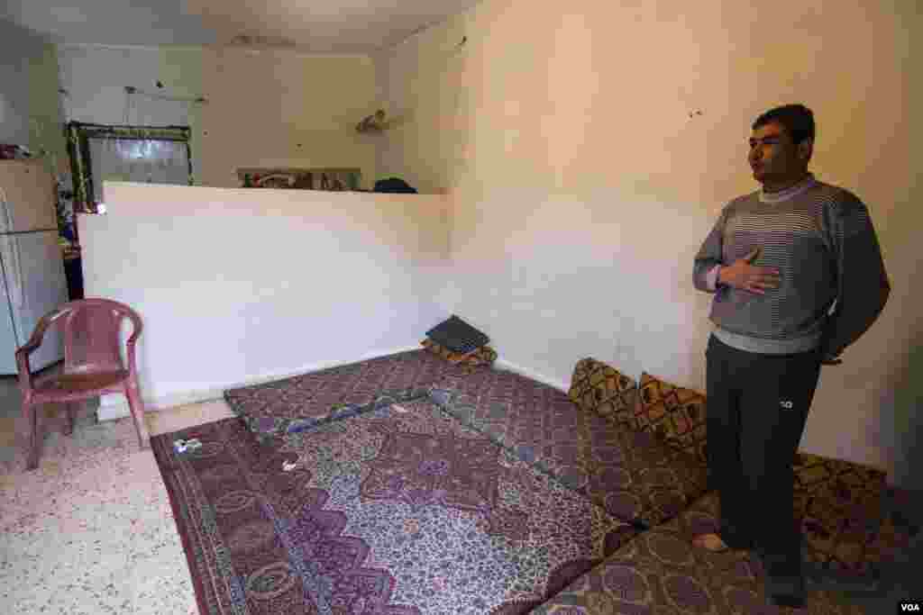 Ahmad in the flat which he shares with his wife and four children. They all sleep in this main room, and struggle to pay the monthly rent of $250, John Owens/VOA.