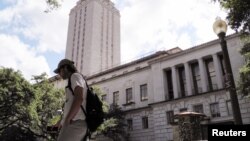 FILE - A student walks past the clock tower at the University of Texas in Austin, Texas, June 23, 2016. On Monday, the state began allowing concealed handguns on public university campuses.