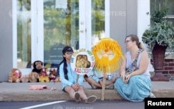 Hayley Hoppe (R) sits with her daughters Piper, 10, (L) and Paisley, 8, (C), in front of the doorway of River Bluff Dental clinic in protest against the killing of a famous lion in Zimbabwe, in Bloomington, Minnesota July 29, 2015. A Zimbabwean court on W
