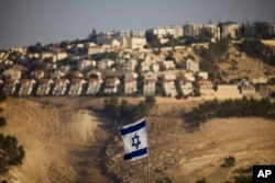 FILE - An Israeli flag is seen near the West Bank Jewish settlement of Maaleh Adumim on the outskirts of Jerusalem in a Sept. 7, 2009, photo.