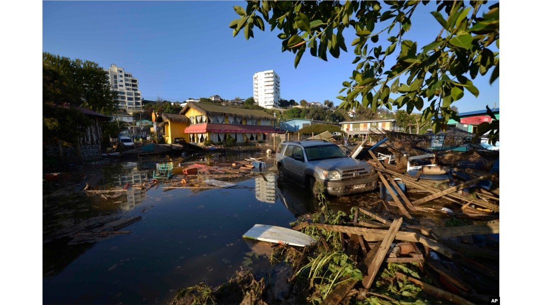 A car is surrounded by debris in a flooded street after an earthquake-triggered tsunami hit Concon, Chile, Sept. 17, 2015.