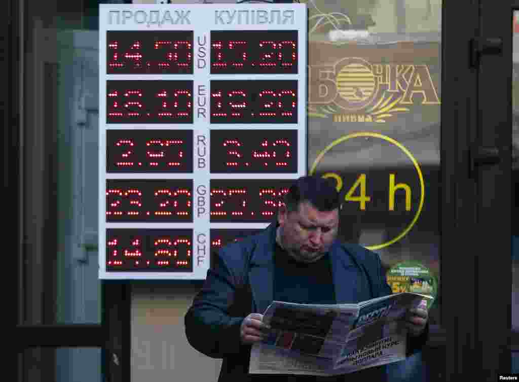 A man reads a newspaper near a currency exchange office in Kyiv. Ukraine&#39;s central bank said it believed the faltering hryvnia currency had fallen to an historic low, Nov. 10, 2014. 