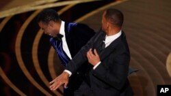 Will Smith, à droite, gifle le présentateur Chris Rock sur scène aux Oscars, le 27 mars 2022, au Dolby Theatre de Los Angeles.