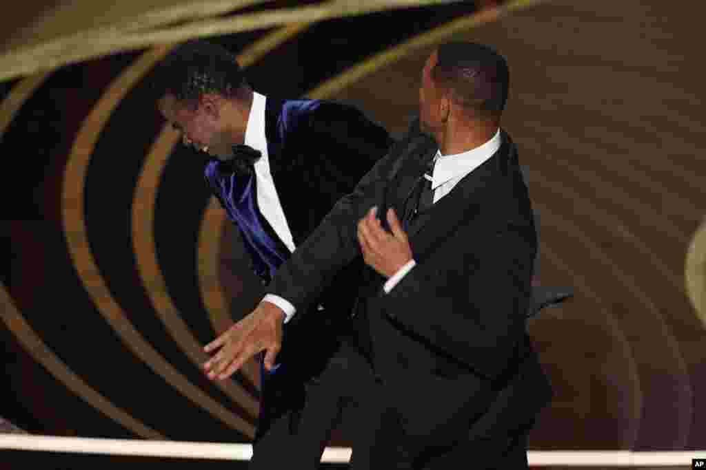 Will Smith, right, hits presenter Chris Rock on stage while presenting the award for best documentary feature at the Oscars, March 27, 2022, at the Dolby Theatre in Los Angeles.