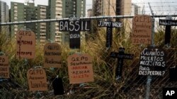 Recortes de cartón, en forma de lápidas y cruces y atados a una valla, llevan mensajes de protesta antigubernamentales y nombres de quienes murieron en protestas, en Caracas, Venezuela, el miércoles 5 de marzo de 2014.