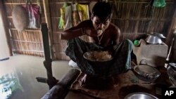 FILE - A boy eats rice inside his house partially submerged in flood waters at Gagolmari village 85 kilometers (53 miles) east of Gauhati, India, Sept. 2, 2015. 