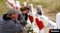 Lorenzo Flores, left, and Terrie Smith react at a line of crosses in remembrance of those killed in the shooting at the First Baptist Church of Sutherland Springs, Texas, Nov. 9, 2017.