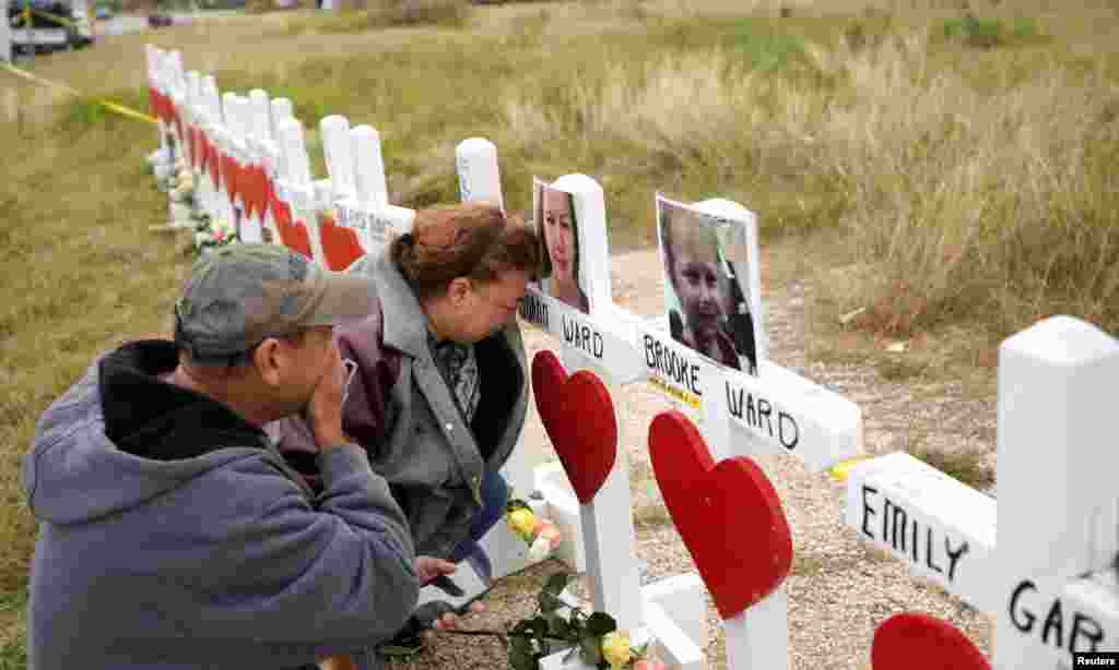 Lorenzo Flores (L) and Terrie Smith react at a line of crosses in remembrance of those killed in the shooting at the First Baptist Church of Sutherland Springs, Texas.