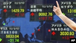 FILE - A man gestures in front of a securities firm's electronic stock board in Tokyo.