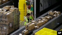 Paket barang pesanan bergerak di sepanjang sistem konveyor dimana kemudian barang-barang tersebut diarahkan ke area pengiriman di Amazon Fulfillment Center yang baru, 9 Februari 2018, di Sacramento, California. (Foto: AP Photo/Rich Pedroncelli)