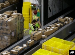 FILE - Packages move down a conveyor system were they are directed to the proper shipping area at the new Amazon Fulfillment Center, Feb. 9, 2018, in Sacramento, California.
