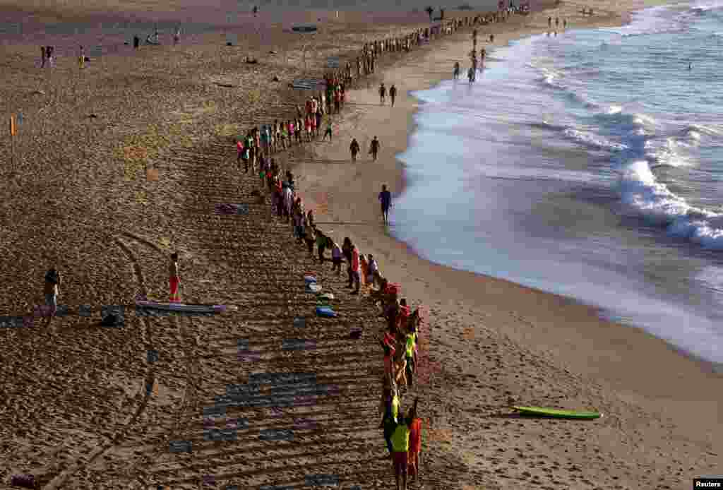 Members of the local surfing community stand in a line to form a 'fluro wave' on the beach of Sydney, Australia. The colorful event was organized to raise awareness and show support for mental disorders on World Mental Health Day. 