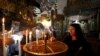 Acendendo uma vela na Igreja da Natividade na cidade de Belém.