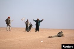 FILE - Men that fled areas of clashes surrender to Syrian Democratic Forces(SDF) fighters north of Raqqa city, Syria, March 8, 2017.