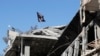 FILE - A flag of Islamic State militants is seen above a destroyed house in Raqqa, Syria, Oct. 18, 2017.