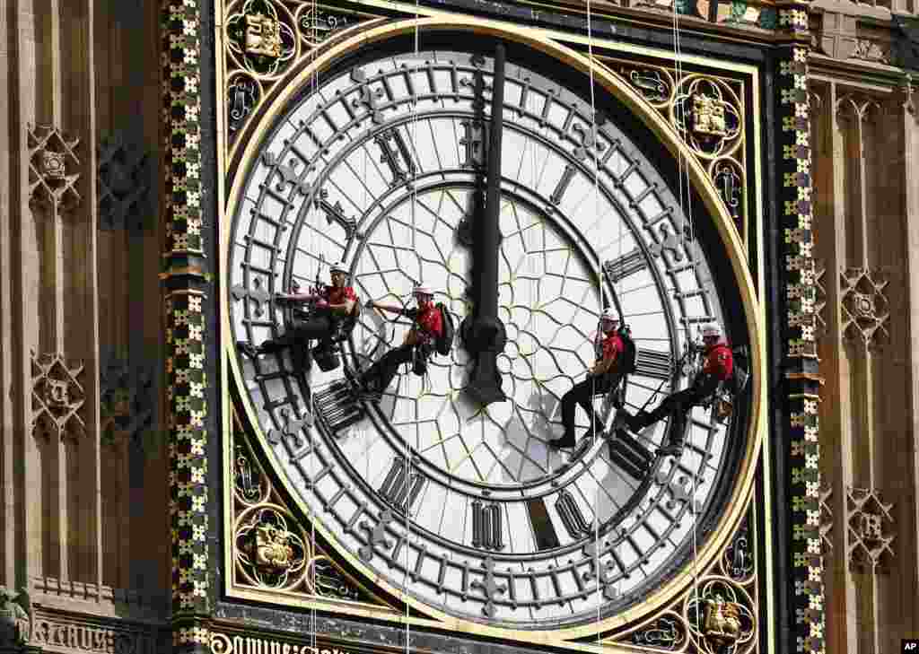 Workers hang outside the clock face as they clean the Big Ben clock tower of the Houses of Parliament in London, Aug. 18, 2014.