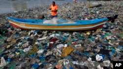 FILE - A fisherman prepares his net on the shores of the Arabian Sea, littered with plastic bags, in Mumbai, India, Oct. 1, 2015. At the Our Ocean summit that concluded Friday, five countries detailed plastic bag bans.