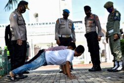 Beberapa orang pria sedang melakukan push up sebagai hukuman karena tidak memakai masker di tengah pandemi Covid-19 di Banda Aceh pada 10 November 2020. (Foto: AFP/Chaideer Mahyuddin)