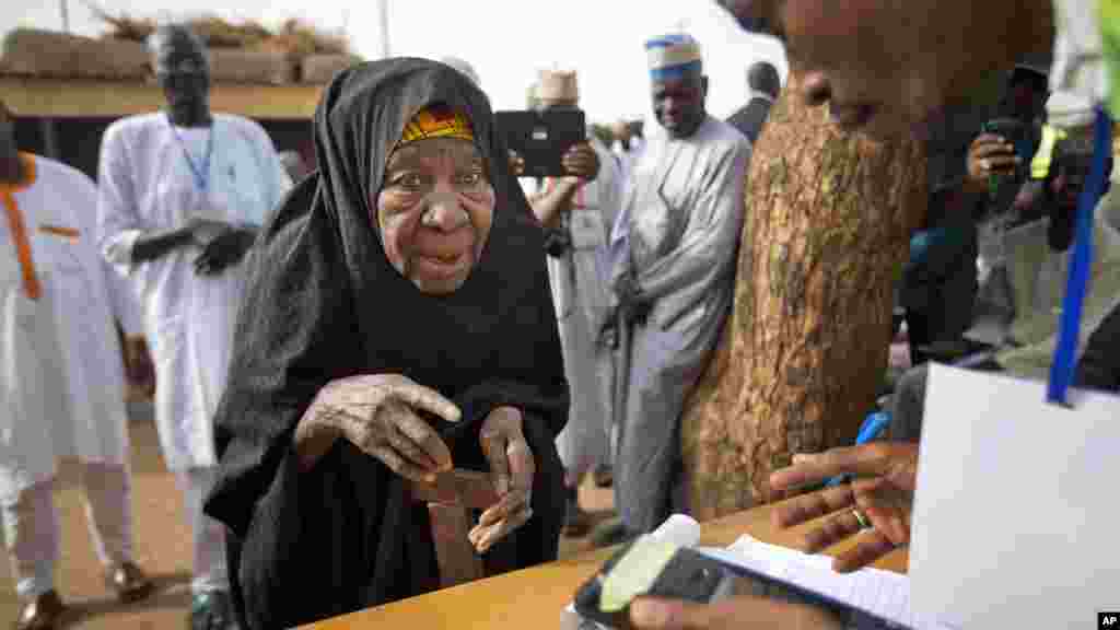 Une vieille femme nigériane fait valider sa carte de vote à travers un lecteur d&#39;empreintes digitales, avant de revenir voter plus tard dans la journée, dans la ville natale du candidat de l&#39;opposition le général Muhammadu Buhari, en Daura, Nigeria samedi 28 mars 2015.