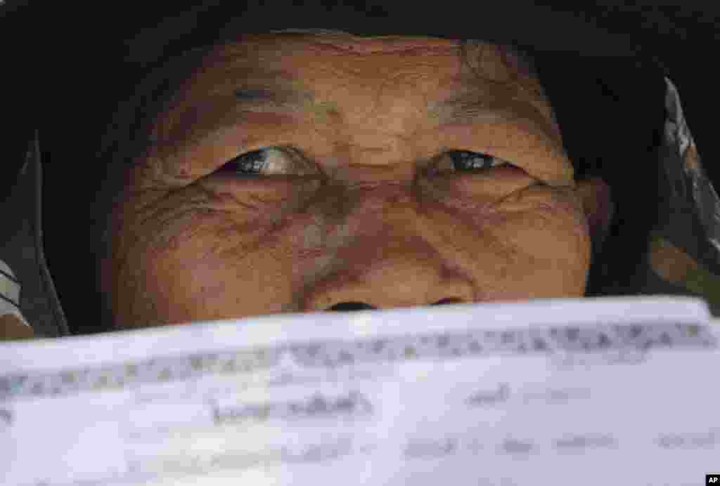 A rice farmer holds her financial statements during a protest demanding payment of a rice subsidy program from the government in Bangkok, Feb. 10, 2014.