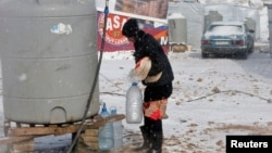 A Syrian refugee carries bread and bottles of water during a winter storm in Zahle town, in the Bekaa Valley, Dec. 11, 2013. 