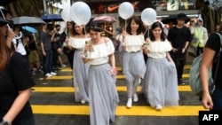 Sekelompok perempuan mengenakan gaun untuk menghadiri pernikahan menyeberangi jalan di tengah demo menentang undang-undang keadaan darurat, di Hong Kong, 12 Oktober 2019. (Foto: AFP)