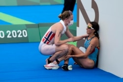 FILE - In this July 27, 2021, file photo, Claire Michel of Belgium is assisted by Lotte Miller of Norway after the finish of the women's individual triathlon competition at the 2020 Summer Olympics, in Tokyo, Japan.