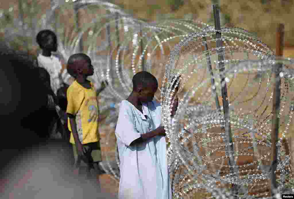 Internally displaced boys stand next to barbed wire inside a United Nation Mission in South Sudan (UNMISS) compound in Juba, Dec. 19, 2013, four days after fighting broke out in the capital city.