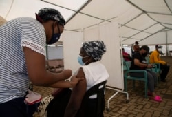 A woman receives a dose of a COVID-19 vaccine at a vaccine center, in Soweto, South Africa, Nov. 29, 2021.