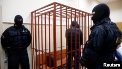 FILE - A defendant stands inside a special cage as he attends a court hearing in Sakhalin, Russia, March 4, 2015. The number of people imprisoned in Russia on extremism-related charges jumped from 137 in 2011 to 414 in 2015, according to independent research.