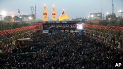 Shi'ite faithful pilgrims gather between, the holy shrine of Imam Abbas and the holy shrine of Imam Hussein, in the background, for Arbaeen in Karbala, 50 miles (80 kilometers) south of Baghdad, Iraq, Nov. 19, 2016. 