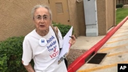 FILE - Rivko Knox, a volunteer with the League of Women Voters, collects signatures, April 19. 2018, for a campaign financing ballot measure outside a polling station in Glendale, Ariz. A judge, Aug. 24, 2018 upheld a 2016 Arizona law that bans groups from collecting early mail-in ballots from voters and delivering them.