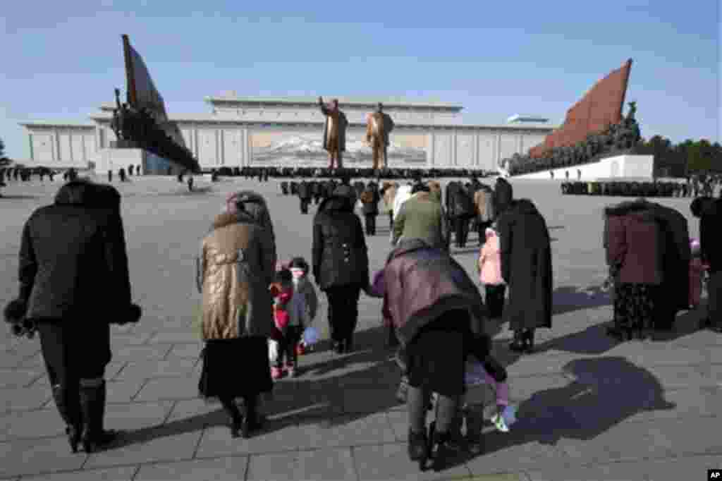 North Koreans bow before the statues of late leaders Kim Il Sung, left, and Kim Jong Il, right, at Mansu Hill in Pyongyang, North Korea, Monday, Dec. 17, 2012.