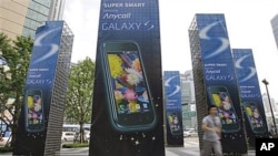 A man runs past Samsung Electronics Co.'s mobile phone Galaxy S advertisement outside its head office in Seoul, South Korea (FILE).