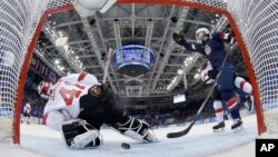 Meghan Duggan of the U.S. celebrates Monique Lamoureux's goal as the puck slides under Goalkeeper Florence Schelling of Switzerland during the second period of the 2014 Winter Olympics women's ice hockey game at Shayba Arena in Sochi, Russia, Feb. 10, 201