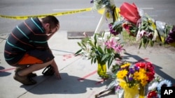 Noah Nicolaisen, of Charleston, S.C., kneels at a makeshift memorial, Thursday, June 18, 2015, down the street from where a man opened fire Wednesday night during a prayer meeting inside the Emanuel AME Church, killing several people. (AP Photo/David Goldman)